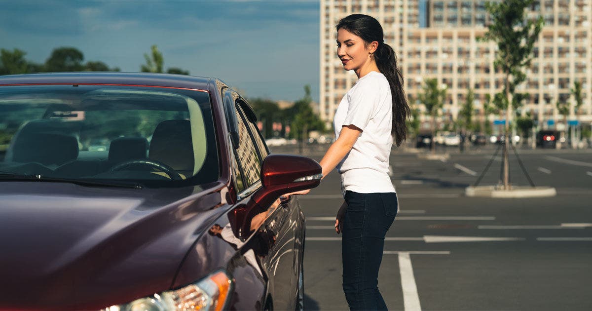 The woman stands near the new car on the parking, The woman stands near the new car on the parking